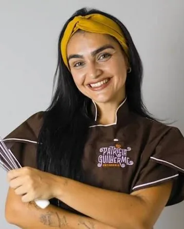 Patricia Guilherme, de dólmã e faixa no cabelo, segurando um batedor de cozinha